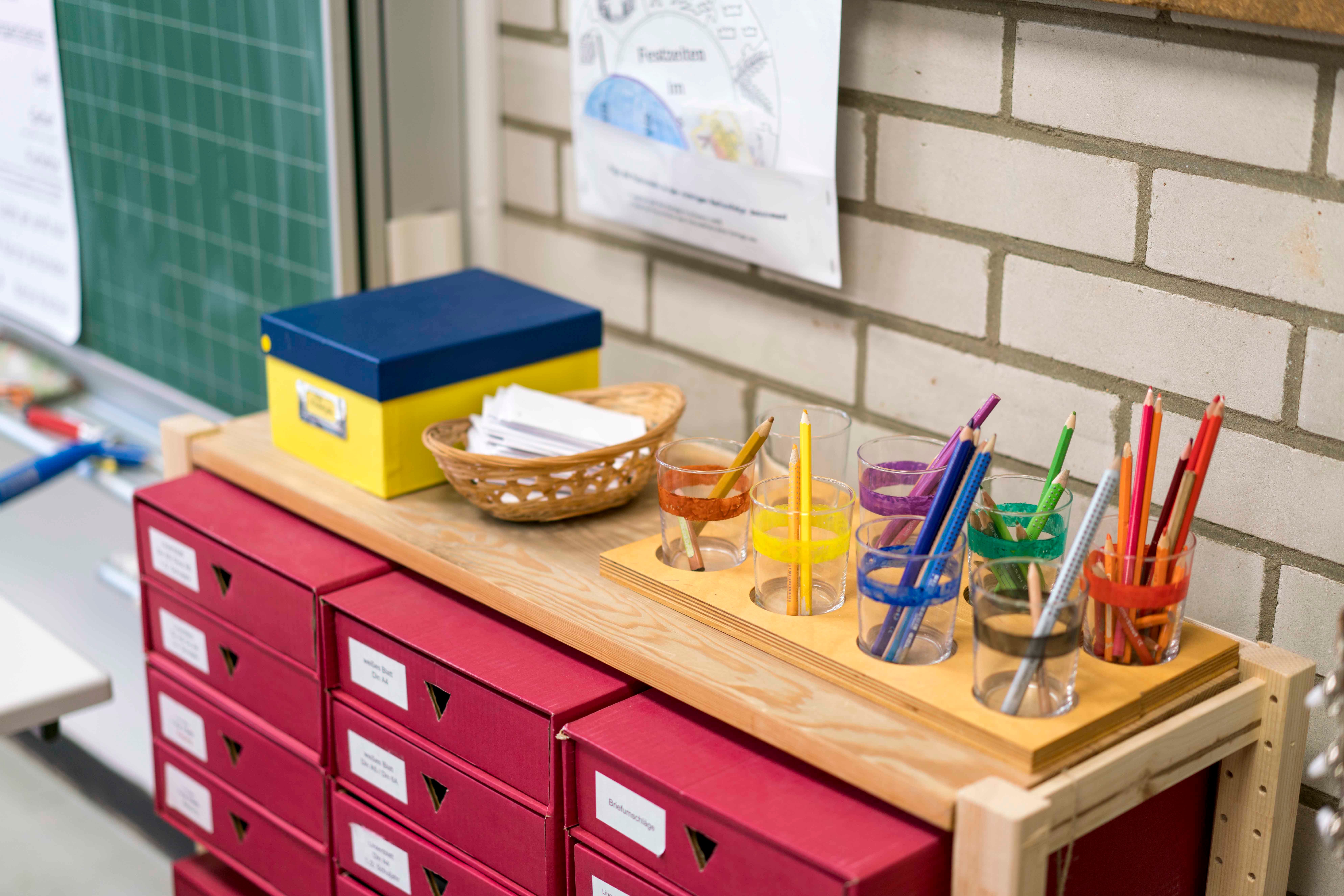 Regal mit Gläsern für farblich sortierte Buntstifte und Papier