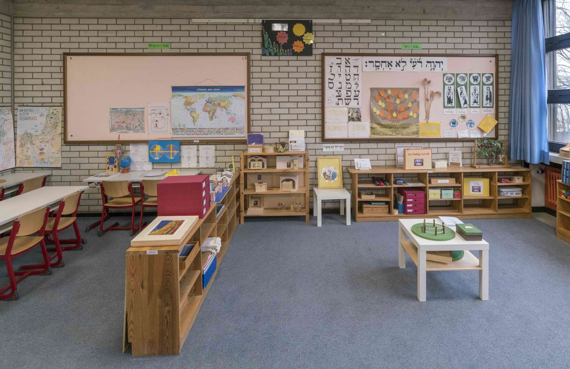 Klassenraum mit offenen Regalen mit Material zu verschiedenen Themen aus Bibel und Liturgie